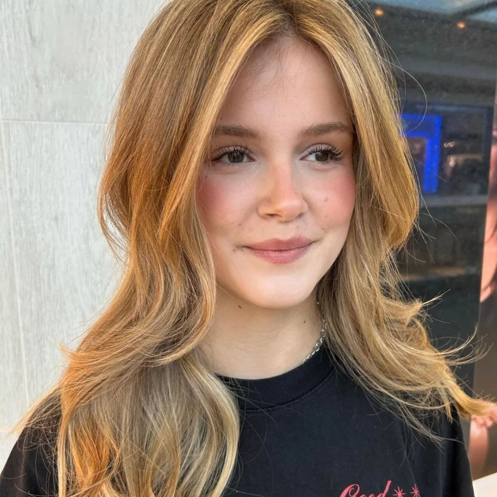 Jeune femme souriante aux cheveux blonds lisses, regardant l'objectif